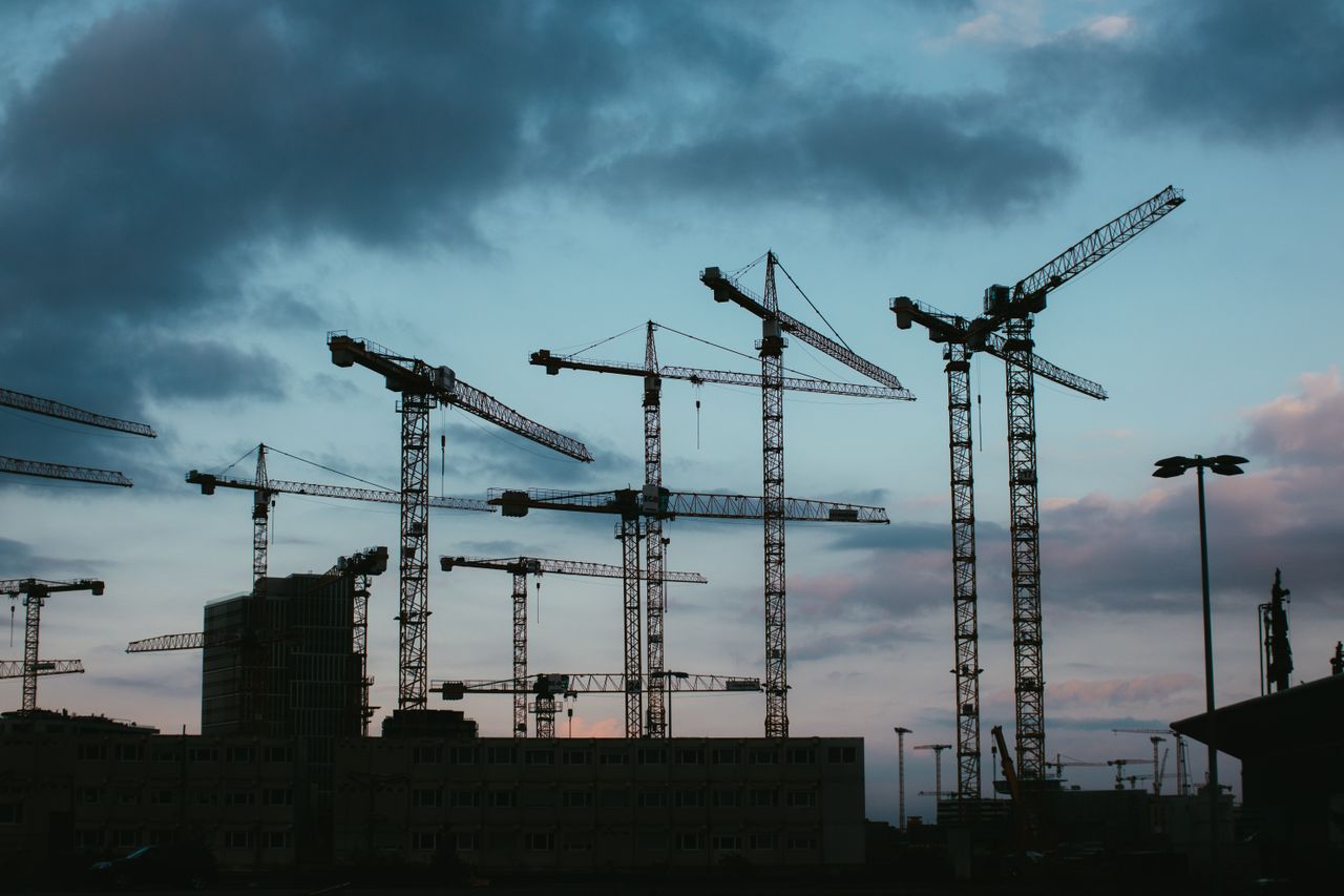 Multiple construction cranes silhouetted against the evening sky, capturing industrial progress.