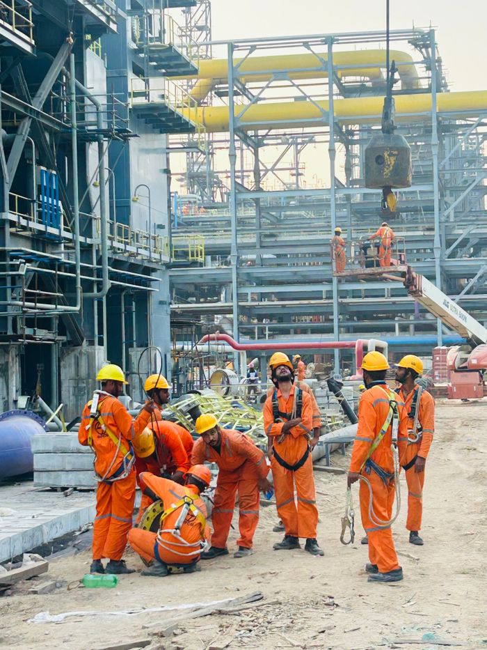 services-01 Group of construction workers in orange uniforms operating at an industrial site.