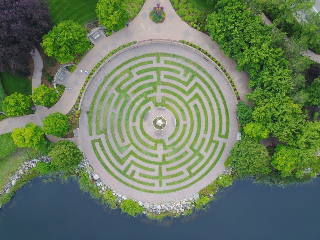 services-04 Discover an aerial perspective of a circular garden maze surrounded by greenery and water.